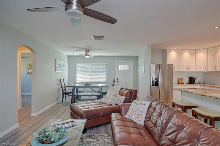 Living area with arched walkways, light wood-style floors, and ceiling fan