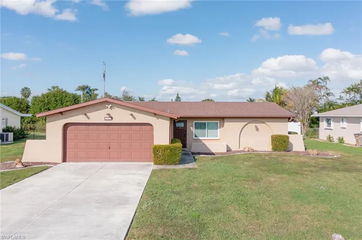 View of front facade with stucco siding, a front lawn, a garage, and driveway