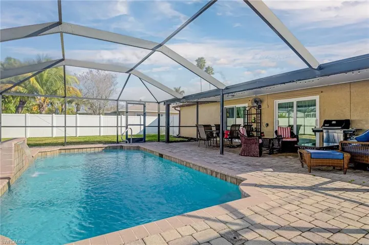 View of pool featuring a sunroom, a lanai, a grill, and patio surround