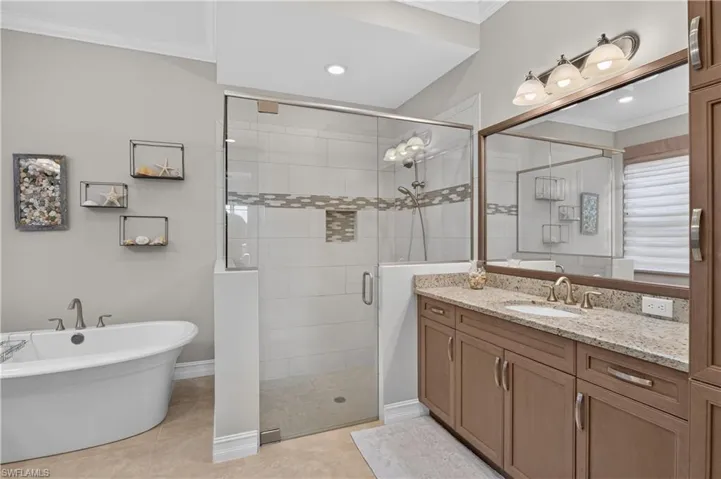 Primary bathroom with his and her vanities, free standing bathtub, and glass shower.