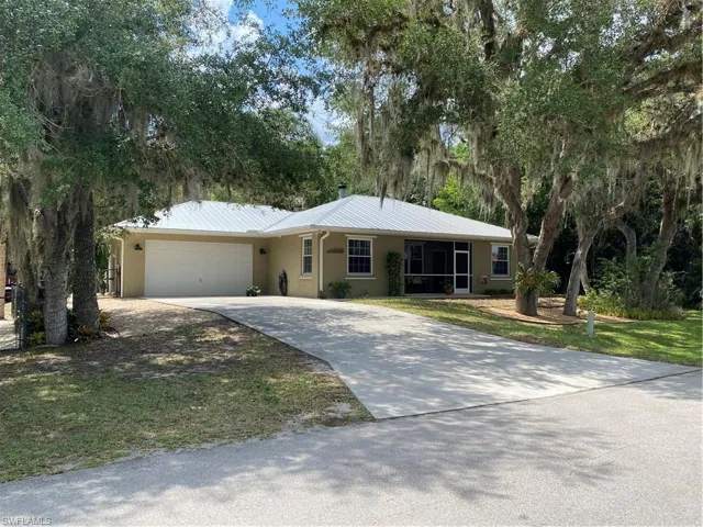 Single story home featuring an attached garage, stucco siding, driveway, and a metal roof