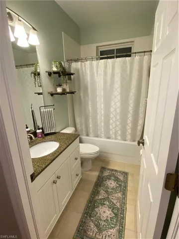 Bathroom featuring vanity, shower / bath combo, and tile patterned floors