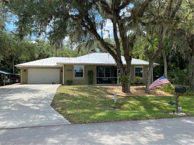 Ranch-style house with stucco siding, a garage, driveway, and a front lawn