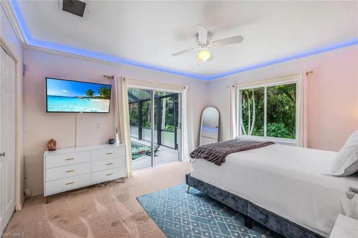 Bedroom with light carpet, access to exterior, multiple windows, and ceiling fan