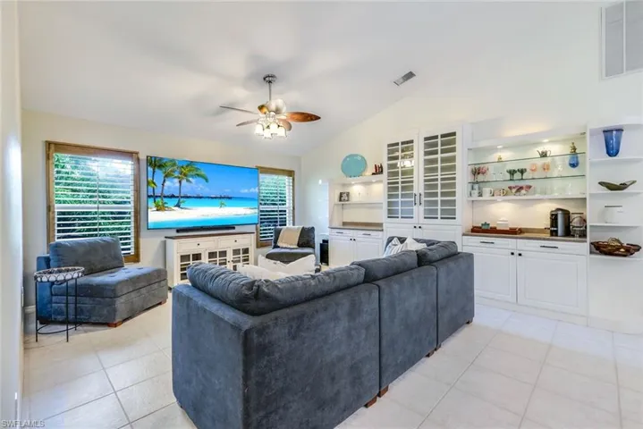 Living room with ceiling fan, lofted ceiling, and light tile floors