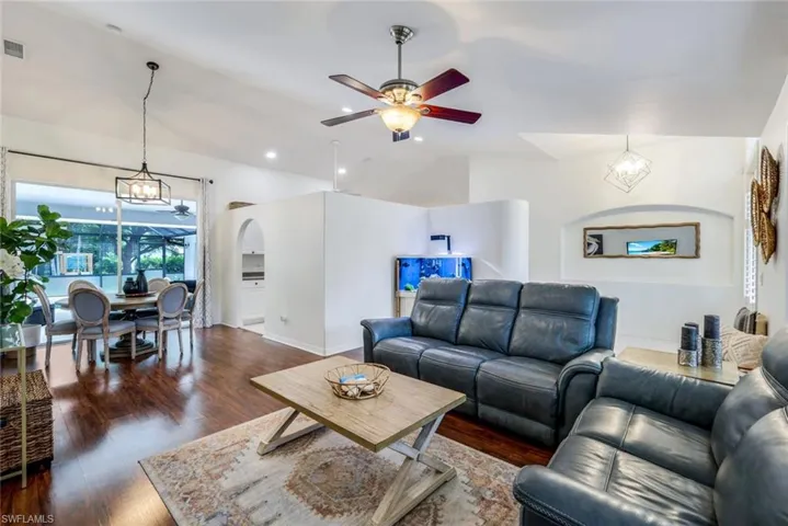 Living room featuring lofted ceiling, dark hardwood / wood-style floors, and ceiling fan with notable chandelier