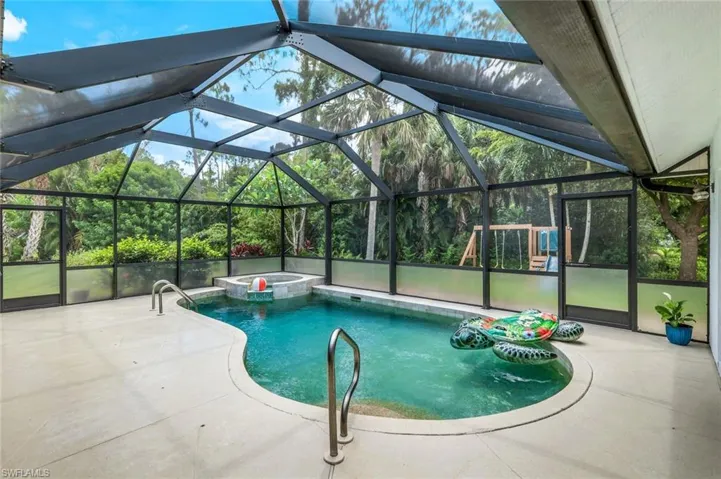 View of swimming pool featuring a patio and glass enclosure