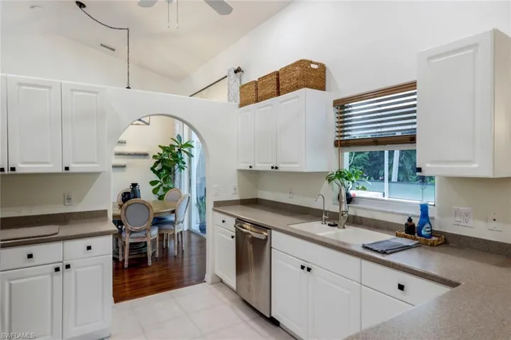 Kitchen featuring white cabinetry, lofted ceiling, ceiling fan, dishwasher, and light tile floors