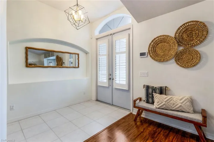 Tiled foyer entrance with a chandelier and french doors