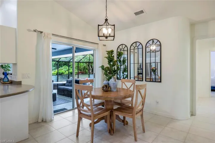 Tiled dining space featuring vaulted ceiling and an inviting chandelier