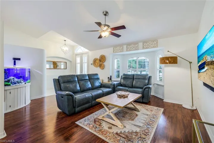 Living room with ceiling fan, vaulted ceiling, and dark hardwood / wood-style flooring
