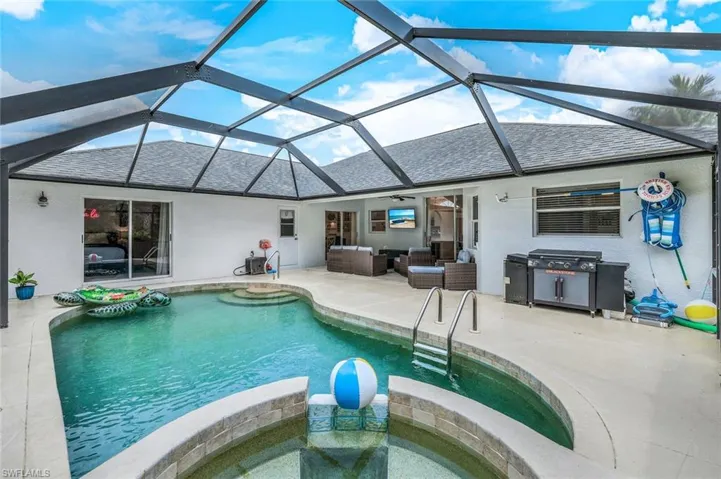 View of pool with a patio, glass enclosure, an outdoor hangout area, and a jacuzzi