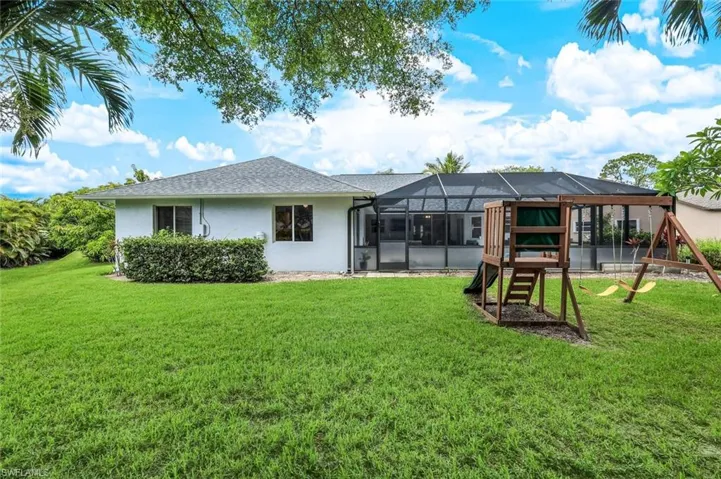 Rear view of property with glass enclosure and a lawn