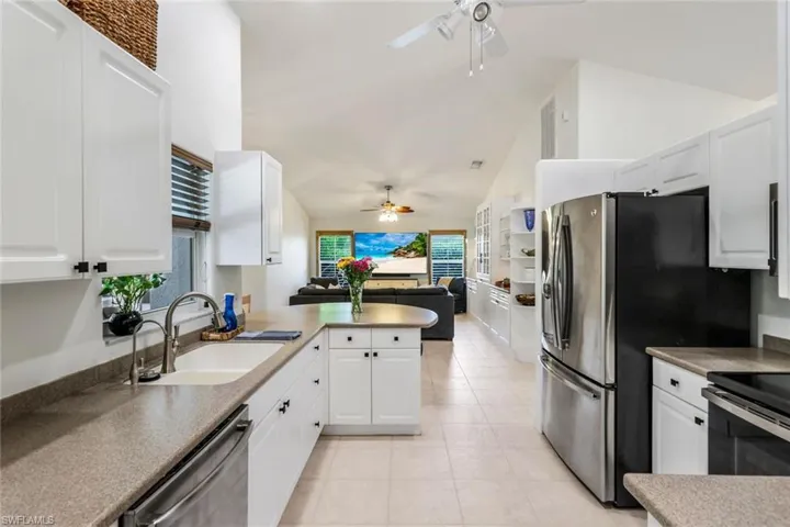 Kitchen featuring appliances with stainless steel finishes, white cabinetry, ceiling fan, and lofted ceiling