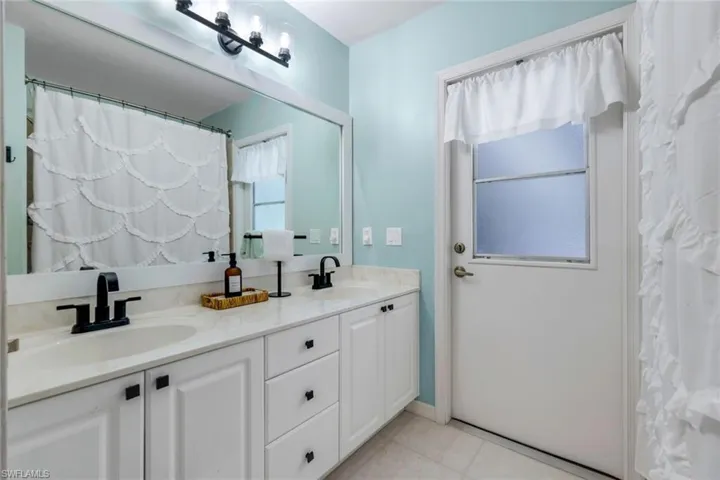 Bathroom with vanity with extensive cabinet space, double sink, and tile flooring