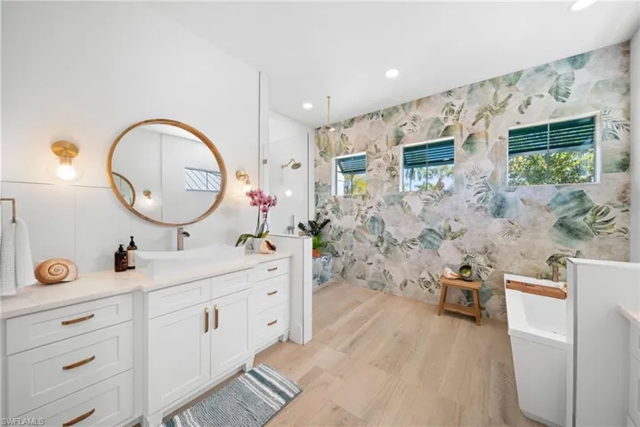 Full bath with walk in shower, a freestanding bath, recessed lighting, vanity, and healthy amount of natural light