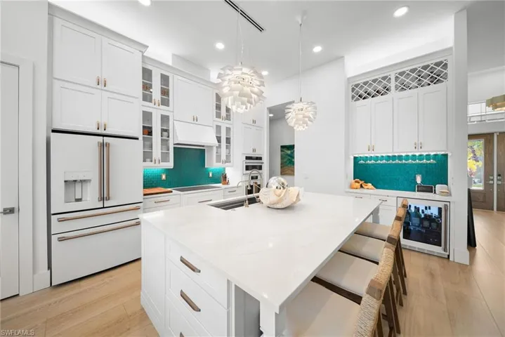 Kitchen featuring high end fridge, glass insert cabinets, and white cabinets