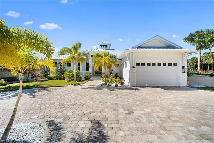View of front of house with decorative driveway, an attached garage, and a standing seam roof