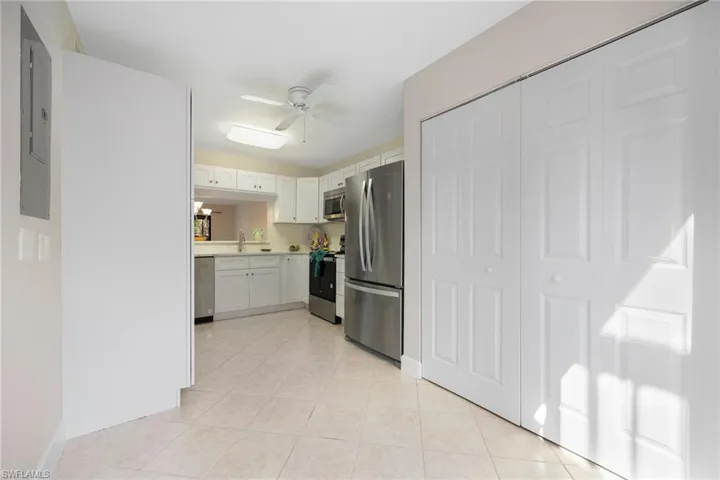 Kitchen with sink, white cabinets, light tile patterned floors, ceiling fan, and stainless steel appliances