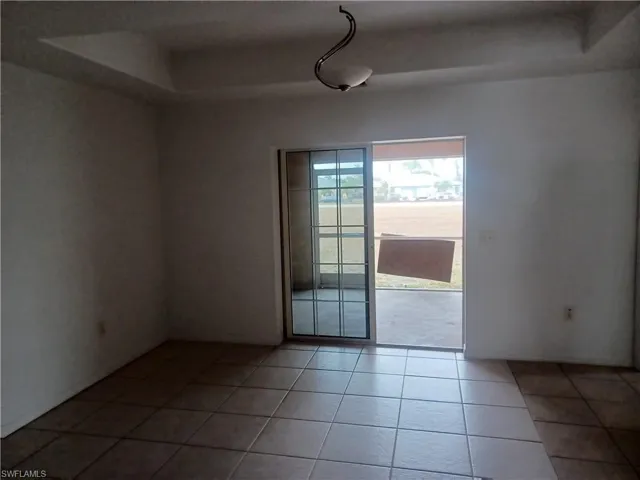 Empty room featuring light tile patterned floors and a tray ceiling