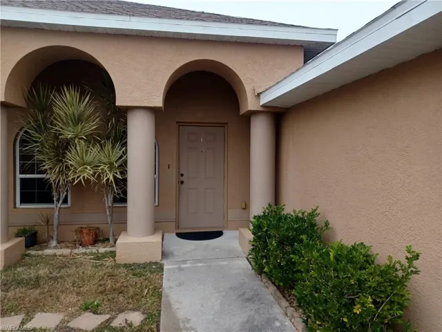 Doorway to property with stucco siding and a shingled roof