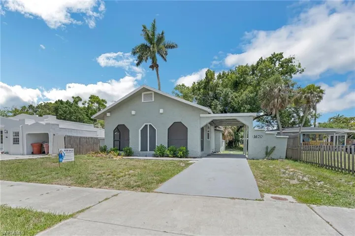 View of front of house with stucco siding, concrete driveway, and a carport