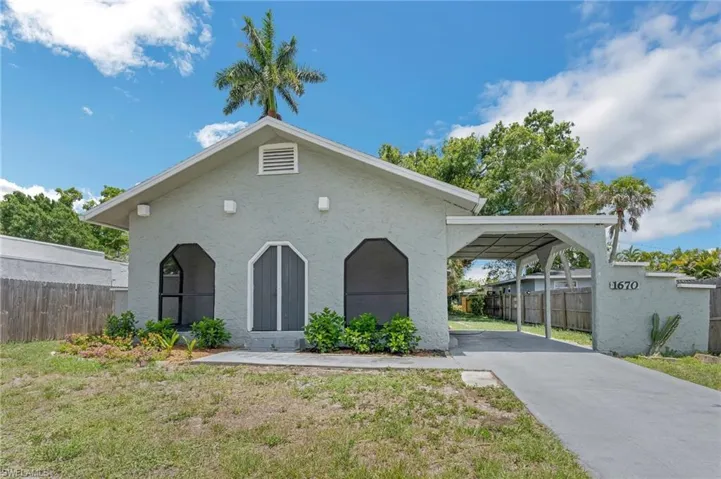 View of front of house with stucco siding, concrete driveway, and a carport