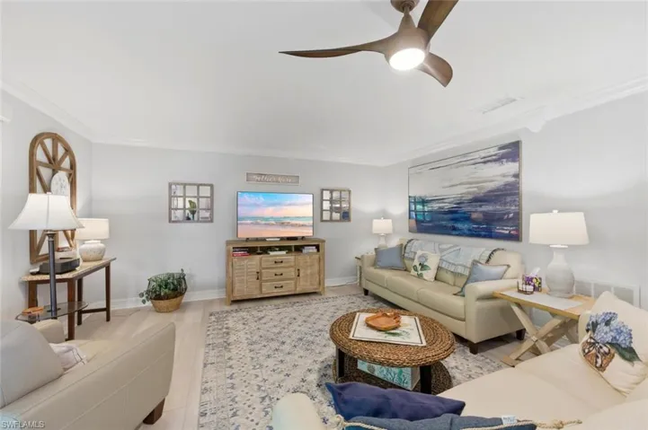 Living room with ceiling fan, crown molding, and wood finished floors