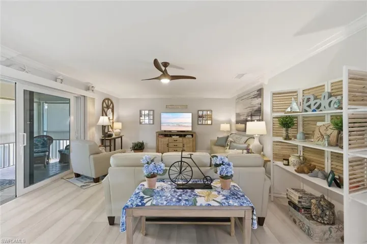 Living room with crown molding, ceiling fan, and light wood-style flooring