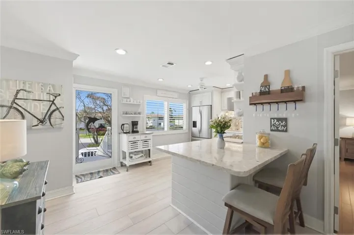 Kitchen with a kitchen bar, open shelves, a peninsula, crown molding, and light stone counters