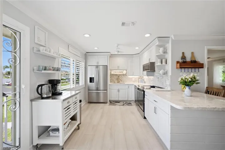 Kitchen with open shelves, stainless steel appliances, white cabinets, backsplash, and crown molding