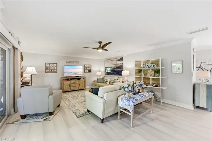 Living room with ornamental molding, ceiling fan, and light wood-style flooring