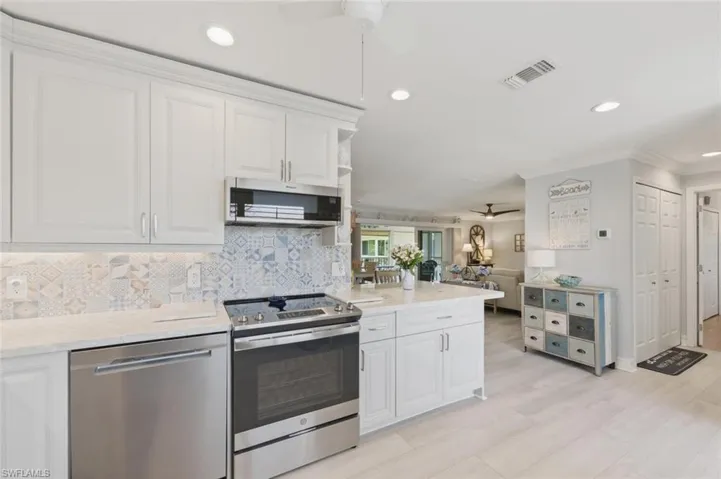 Kitchen featuring ceiling fan, stainless steel appliances, white cabinetry, crown molding, and recessed lighting