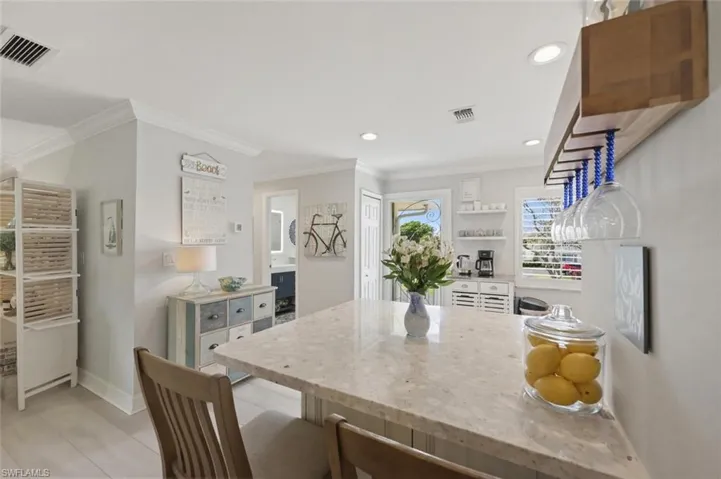 Kitchen with a breakfast bar area, a peninsula, light stone counters, recessed lighting, and white cabinets