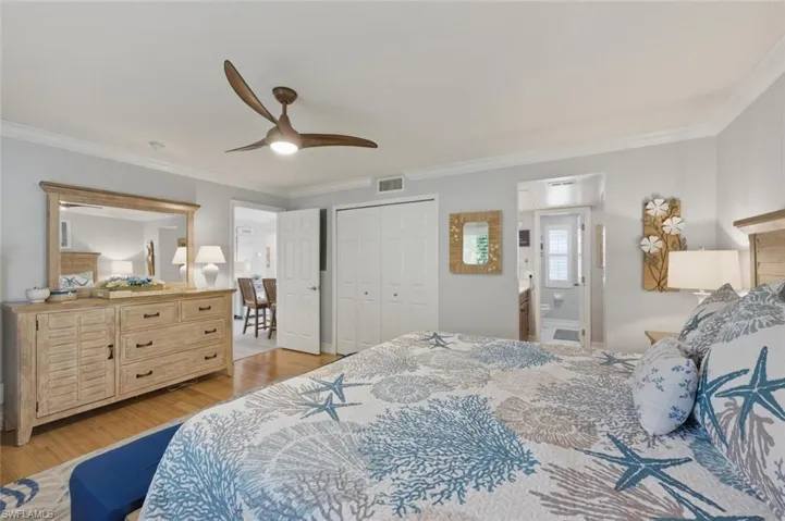 Master Bedroom with ornamental molding, light wood-style flooring, a ceiling fan, a closet, and ensuite bath