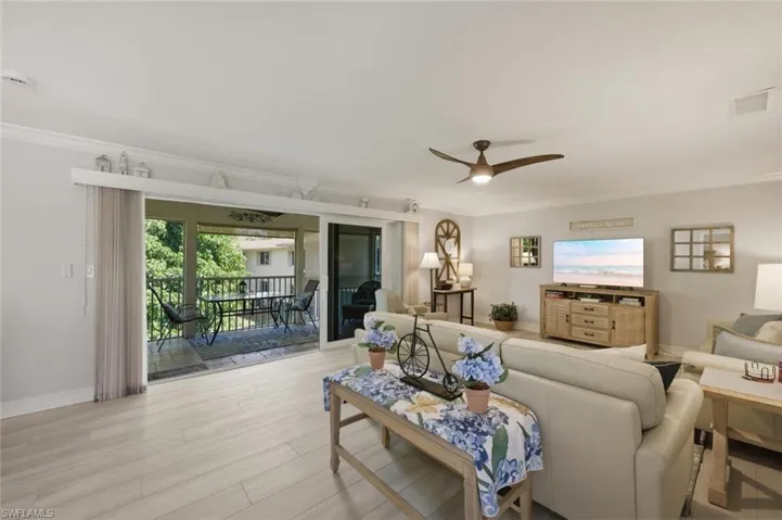 Living area featuring ceiling fan, light wood-type flooring, and crown molding
