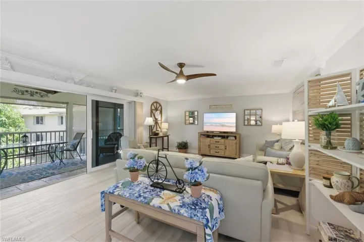 Living area featuring a ceiling fan, light wood-type flooring, and ornamental molding