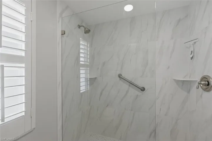 Full master bathroom featuring plenty of natural light and a marble finish shower