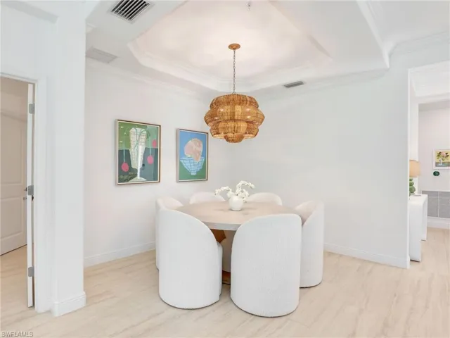 Dining room with a chandelier, baseboards, a raised ceiling, and crown molding