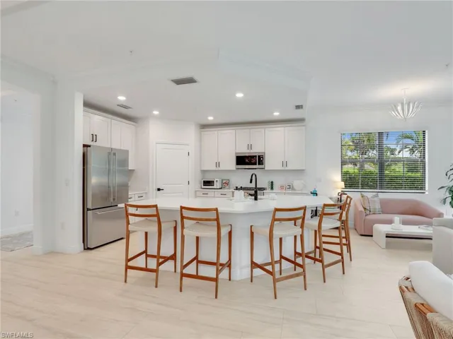 Kitchen with appliances with stainless steel finishes, crown molding, light countertops, recessed lighting, and a breakfast bar