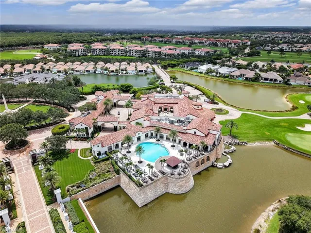 Aerial view of residential area with a large body of water, a golf course, and a pool area