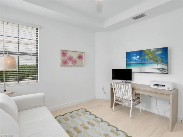 Office space with wood finished floors, baseboards, and a tray ceiling