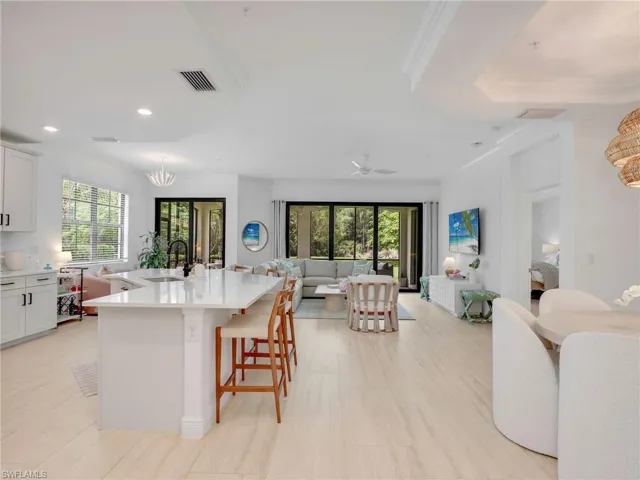 Kitchen with open floor plan, crown molding, light countertops, recessed lighting, and a sink