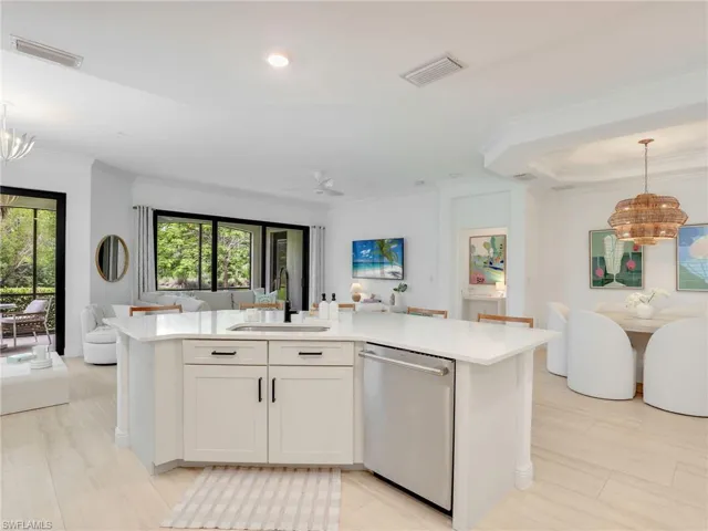 Kitchen with dishwasher, open floor plan, a sink, a chandelier, and ornamental molding