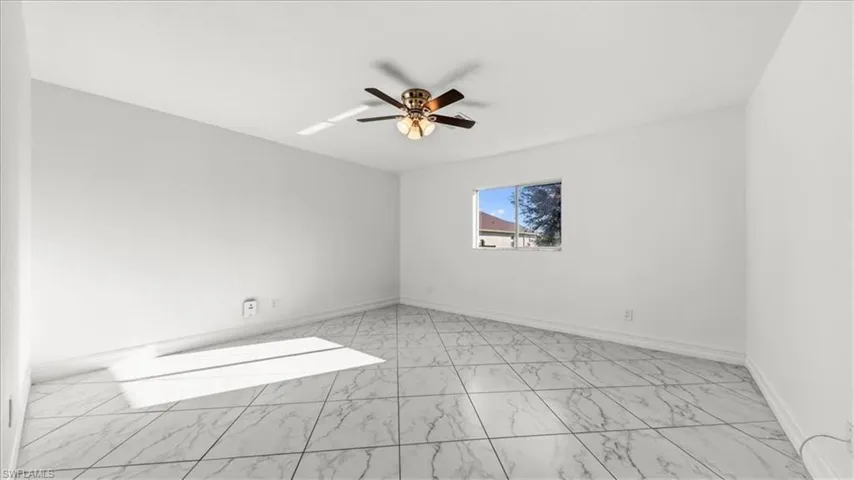 Unfurnished room featuring light marble finish flooring and ceiling fan