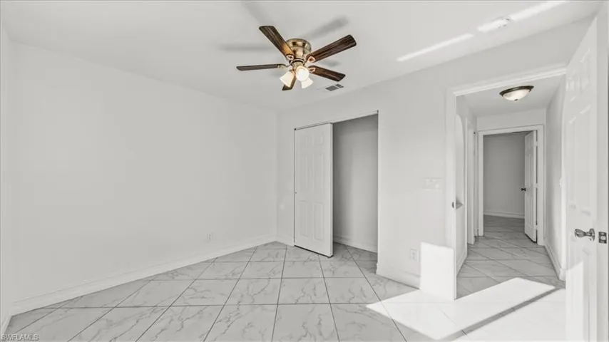 Unfurnished bedroom with light marble finish floors, a closet, and ceiling fan