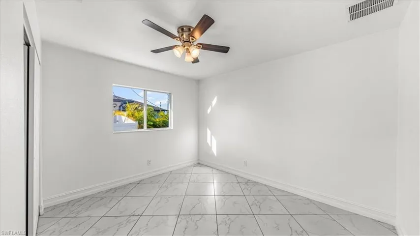 Spare room featuring light marble finish floors and a ceiling fan