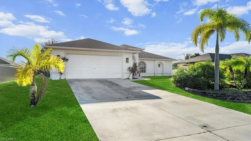 Ranch-style house featuring stucco siding, driveway, an attached garage, and a front lawn