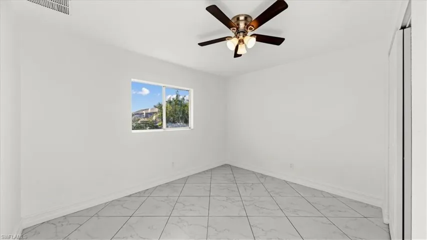 Empty room featuring light marble finish flooring and ceiling fan