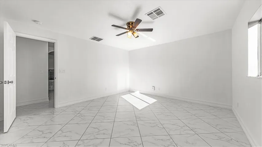 Empty room with light marble finish floors and a ceiling fan